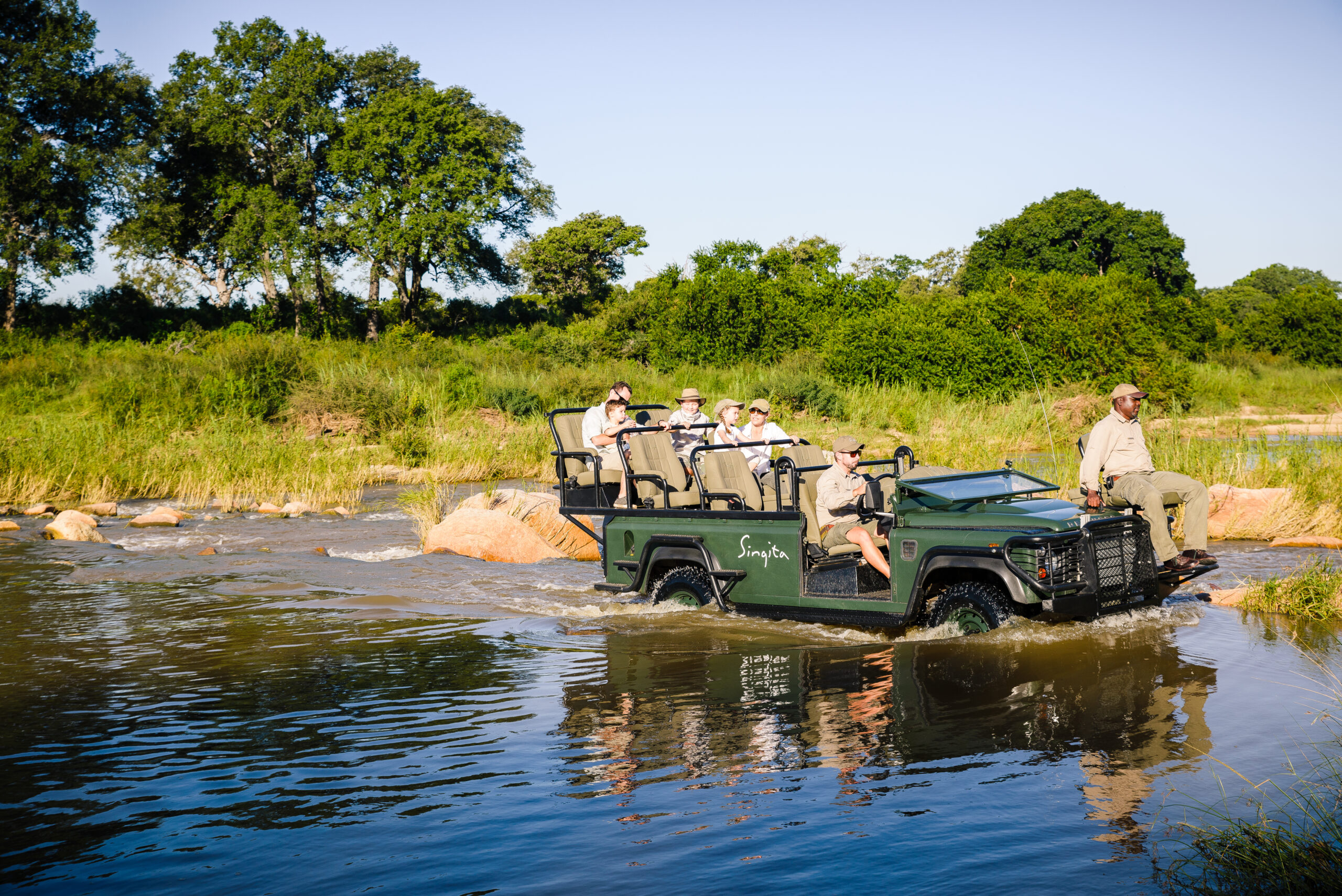 Singita Sabi Sand_Game Drive_Family on Vehicle driving through River_Ross Couper